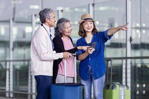 Gruppe von asiatisch Familie Tourist Passagier mit Senior ist mit Handy, Mobiltelefon Anwendung zu Anruf wählen oben Taxi beim Flughafen Terminal zum Transport während ihr Ferien Reise und lange Wochenende Urlaub foto