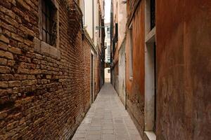 typisch eng Straße mit historisch Häuser im Venedig. eng Fußgänger Straßen von Venedig zwischen das Kanäle. foto