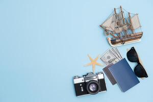 oben Aussicht Reise Konzept mit retro Kamera Filme, Smartphone, Karte, Reisepass, Kompass und Outfit von Reisender auf Blau Hintergrund mit Kopieren Raum, Tourist wesentliche, Jahrgang Ton bewirken foto