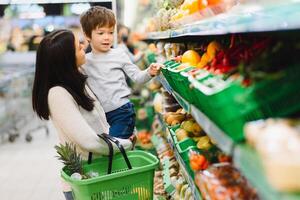 Frau und Kind Junge während Familie Einkaufen mit Wagen beim Supermarkt foto