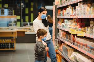 jung Frau und ihr Kind tragen schützend Gesicht Masken Geschäft ein Essen beim ein Supermarkt während das Coronavirus Epidemie oder Grippe Ausbruch. foto