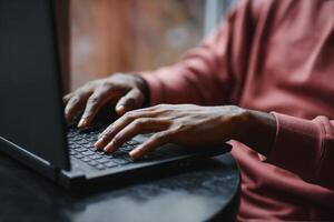 afrikanisch amerikanisch Mann Arbeiten auf Laptop im ein Cafe. foto