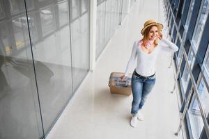 Mädchen Reisender Gehen mit Tragen halt Koffer im das Flughafen. Tourist Konzept. Frau Spaziergänge durch Flughafen Terminal mit Gepäck. Reise Konzept foto