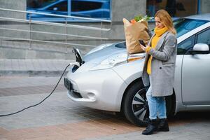 Frau Laden Elektro Auto beim das elektrisch Gas Bahnhof. foto