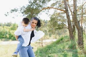 glücklich jung Mutter ist spielen mit ihr Baby im ein Park auf ein Grün Rasen. Glück und Harmonie von Familie Leben. großartig Familie Urlaub. gut Wochenende. Mütter Tag. Urlaub. das Konzept von ein glücklich Familie foto