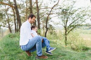 glücklich Zeit mit Vater. Familie Spaß Konzept. bärtig Mann und süß Sohn Kinder lächeln. Frühling Zeit gehen mit Vater. foto