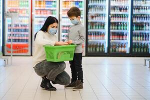 Porträt von ein Mutter und ihr wenig Sohn tragen schützend Gesicht Maske beim ein Supermarkt während das Coronavirus Epidemie oder Grippe Ausbruch. leeren Raum zum Text foto