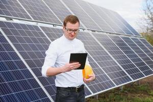 Solar- Energie. jung Geschäft Mann im ein Weiß Hemd in der Nähe von das Solar- Paneele zu Leistung Pflanzen. foto