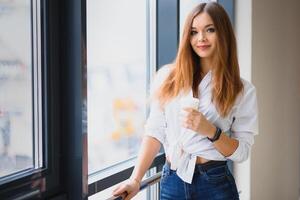 ziemlich Mädchen haben Kaffee durch das Fenster foto