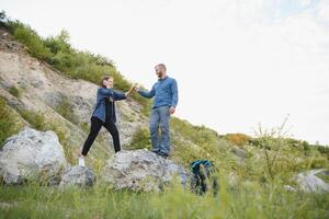 ein Paar von Touristen im Zeit von Ausflug Stahl und bewundern das schön Berg Landschaft. das Kerl Umarmungen das Mädchen. das Konzept von Liebe, Zärtlichkeit und Erholung foto