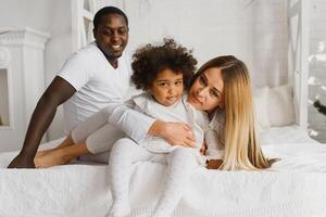 glücklich interracial Paar mit ihr wenig Tochter beim Zuhause foto
