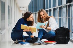 weiblich Studenten Sitzung auf das Fußboden und lesen Anmerkungen Vor Prüfung foto