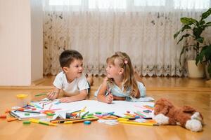 Kinder Zeichnung auf Fußboden auf Papier. Vorschule Junge und Mädchen abspielen auf Fußboden mit lehrreich Spielzeuge - - Blöcke, Zug, Eisenbahn, Ebene. Spielzeuge zum Vorschule und Kindergarten. Kinder beim Zuhause oder Kindertagesstätte foto