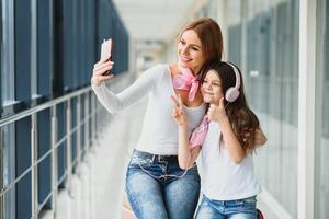 Mama mit ihr Tochter beim das Flughafen warten zum ein Flugzeug und nehmen Selfies foto