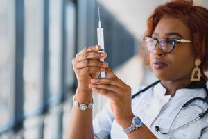 afrikanisch amerikanisch weiblich Arzt halten Spritze mit Injektion foto