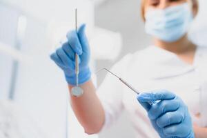 Porträt von ein Zahnarzt halten Dental Instrumente im seine Hände im das Klinik Nahansicht foto