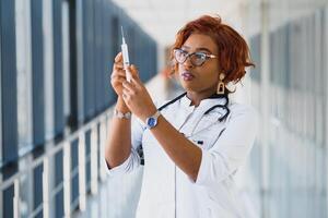 afrikanisch amerikanisch weiblich Arzt halten Spritze mit Injektion foto