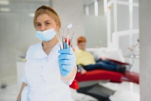 Porträt von ein Zahnarzt halten Dental Instrumente im seine Hände im das Klinik Nahansicht foto