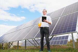Solar- Energie. jung Geschäft Mann im ein Weiß Hemd in der Nähe von das Solar- Paneele zu Leistung Pflanzen. foto