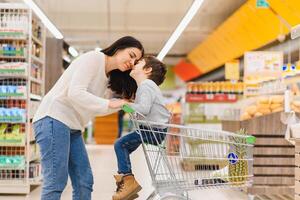 Frau und Kind Junge während Familie Einkaufen mit Wagen beim Supermarkt foto