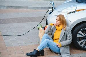 Frau Laden Elektro Auto beim das elektrisch Gas Bahnhof. foto