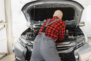 Mechaniker Arbeiten und halten Schlüssel von Bedienung bestellen zum Aufrechterhaltung Auto beim das Reparatur Geschäft foto