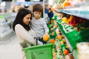 Mutter und Kind Einkaufen beim Landwirte Markt zum Früchte und Gemüse foto