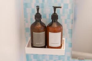Toilettenartikel Flaschen im Badezimmer beim Luxus Hotel oder modern heim. Dusche Container Satz, Körper Seife und Haar Conditioner mit Marmor Mauer Hintergrund foto