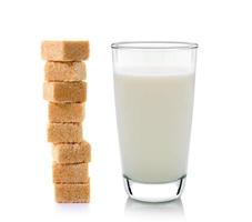 Glas Milch und Rohrzuckerwürfel auf weißem Hintergrund foto