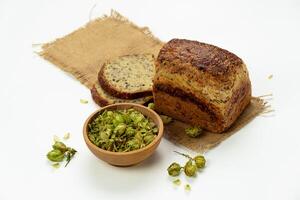 organisch Brot von ganze Korn Mehl und hop Sauerteig. trocken hop Blumen im hölzern Schüssel und hausgemacht Brot. Kunst Bäckerei Konzept foto