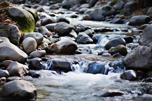 ai generiert ein klar Berg Strom fließend Über glatt Felsen, Darstellen das Reinheit und Bedeutung von natürlich Wasser Quellen. generativ ai foto