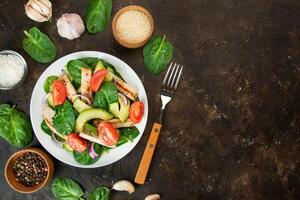 ein gesund Salat von Hähnchen Brust, frisch Gemüse, Spinat Blätter, Avocado und Tomaten auf ein dunkel Hintergrund. Salat von Grüns mit Fleisch. das Konzept von Diät Lebensmittel. Kopieren Raum. benner Lebensmittel. foto