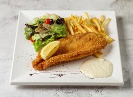 knusprig Fisch und Chips mit Zahnstein Soße, Limette und Salat serviert im Gericht isoliert grau Hintergrund oben Aussicht Singapur schnell Essen foto