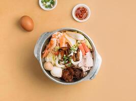 Tom lecker xiao wan im ein Schüssel mit Suppe, Chili Soße und Frühling Zwiebel oben Aussicht auf hölzern Tabelle foto