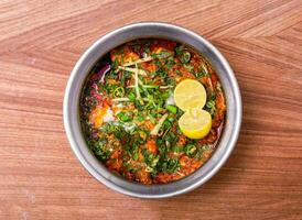 Hähnchen Karahi Masala mit Zitrone Scheibe serviert im Gericht isoliert auf grau Hintergrund oben Aussicht von pakistanisch Essen foto