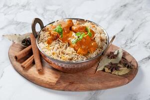 indisch würzig Butter Hähnchen Biryani serviert im ein Gericht isoliert auf hölzern Tafel Seite Aussicht auf grau Hintergrund foto