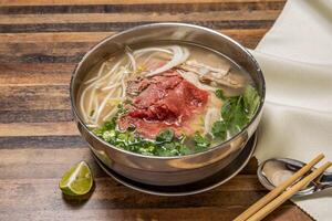 Hanoi Selten Rindfleisch pho Belag mit Zwiebel, Nudeln, Grün Zwiebel, Zitrone und Koriander serviert im Schüssel isoliert auf hölzern Tabelle oben Aussicht von Hong kong schnell Essen foto