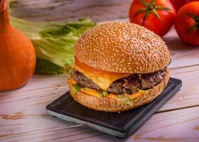 Grill Käse Burger isoliert auf Schneiden Tafel oben Aussicht auf dunkel Hintergrund amerikanisch schnell Essen foto