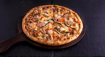 tropisch Hähnchen Käse Pizza isoliert auf Schneiden Tafel oben Aussicht auf dunkel Hintergrund Italienisch schnell Essen foto