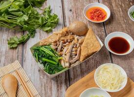 Ente Fleisch Bento umfassen Reis, geschmort Ente, mit Chili Soße, Nudeln, brot, Toast, Löffel und Essstäbchen serviert im Gericht isoliert auf Serviette oben Aussicht von Hong kong Essen foto