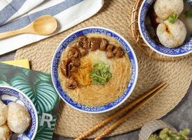 groß Darm mee su Nudeln mit Essstäbchen und Löffel serviert im Schüssel isoliert auf Tabelle oben Aussicht von Chinesisch Essen foto