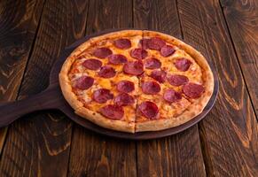 Peperoni Pizza isoliert auf Schneiden Tafel oben Aussicht auf dunkel Hintergrund Italienisch schnell Essen foto