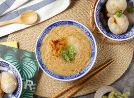 klar Nudeln mit Essstäbchen und Löffel serviert im Schüssel isoliert auf Tabelle oben Aussicht von Chinesisch Essen foto