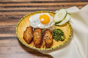 Hähnchen Flügel mit gebraten Ei sonnig Seite oben und Reis serviert im Gericht isoliert auf hölzern Tabelle oben Aussicht von Hong kong schnell Essen foto