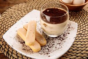 Tiramisu mit Finger Kekse serviert im ein Glas isoliert auf hölzern Hintergrund Seite Aussicht Dessert foto