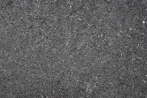 Textur von dunkel Asphalt Straße mit eingebettet Felsen, städtisch Boden Hintergrund. foto