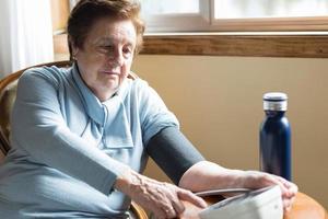 ältere kaukasische Frau über 70, die ihren Blutdruck zu Hause in der Nähe des Fensters überprüft. foto