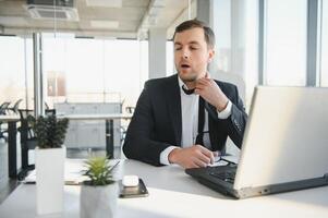 Porträt von betont aus und besorgt lästig überarbeitet Geschäftsmann Unternehmer suchen Unterlagen Bericht im modern hell Büro Arbeiten unter Druck und fest Frist foto