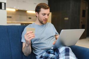 lächelnder Mann beim Online-Einkauf zu Hause foto