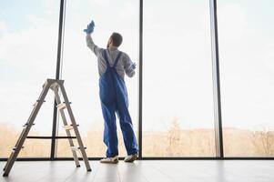 junger mann, der fenster im büro putzt foto